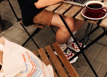 Hombre usando una computadora portátil, sentado en una mesa de un entorno regional chileno tomando café