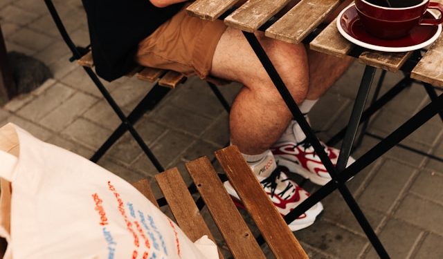 Hombre usando una computadora portátil, sentado en una mesa de un entorno regional chileno tomando café